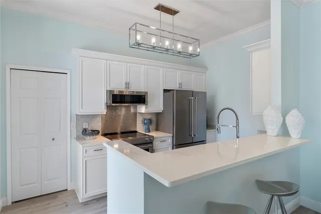 a kitchen with stainless steel appliances a refrigerator a stove a sink dishwasher a dining table and chairs with wooden floor