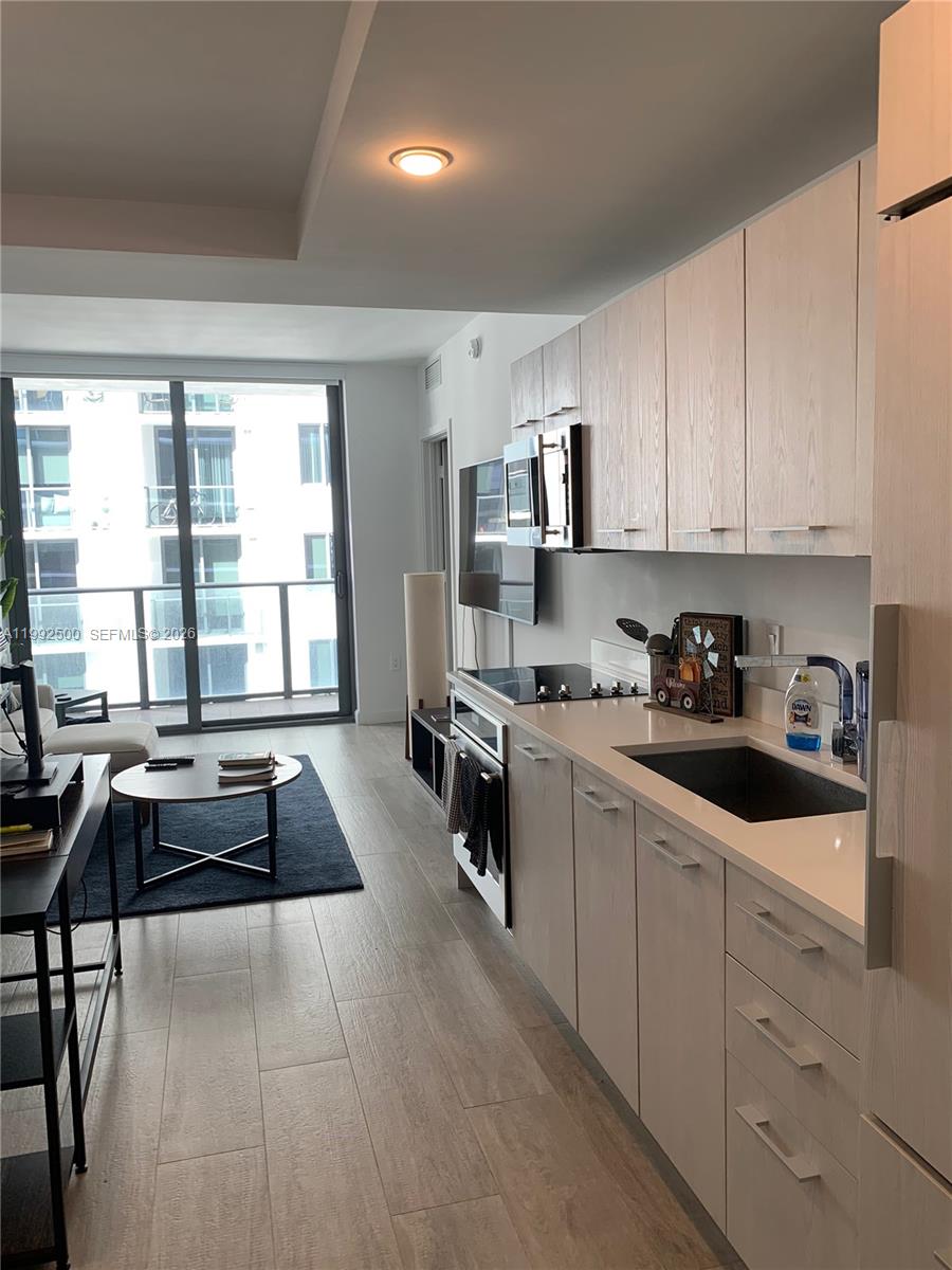 55 Southwest 9th Street, Unit 3709 Miami, FL 33130 - Photo 50 of 52 a kitchen with granite countertop a stove a sink a refrigerator and white cabinets