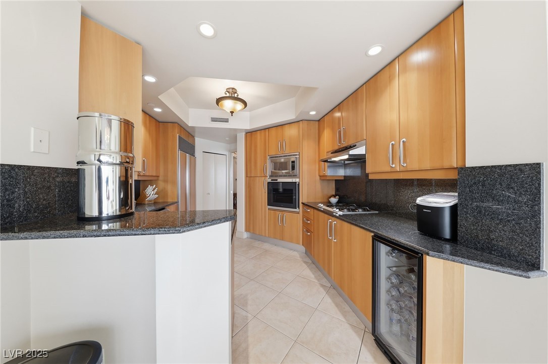 2747 Paradise Road, Unit 1205 Las Vegas, NV 89109 - Photo 15 of 32 Kitchen with backsplash, dark stone counters, wine cooler, a tray ceiling, and built in appliances