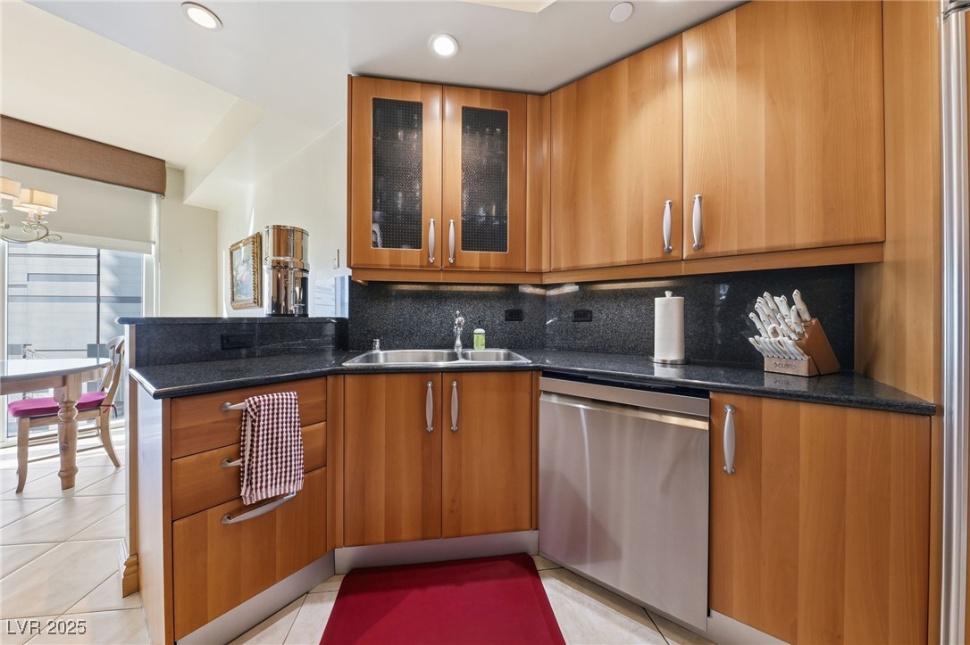 2747 Paradise Road, Unit 1205 Las Vegas, NV 89109 - Photo 16 of 32 Kitchen with decorative backsplash, glass insert cabinets, stainless steel dishwasher, light tile patterned floors, and modern cabinets