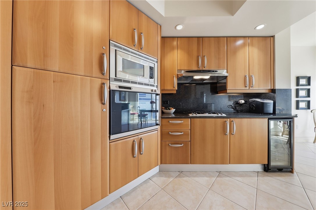 2747 Paradise Road, Unit 1205 Las Vegas, NV 89109 - Photo 17 of 32 Kitchen with wall oven, light tile patterned flooring, stainless steel microwave, wine cooler, and dark stone countertops