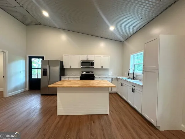 a large white kitchen with cabinets stove top oven and sink
