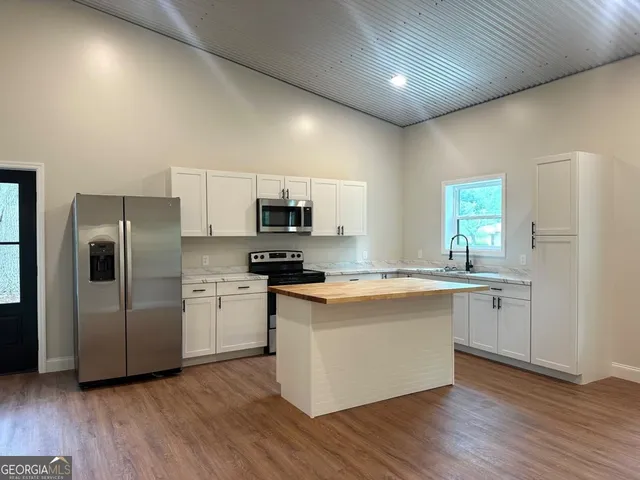 a large kitchen with stainless steel appliances a sink a refrigerator and microwave