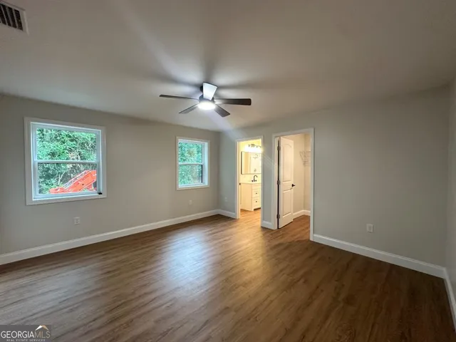 a view of an empty room with a window and wooden floor