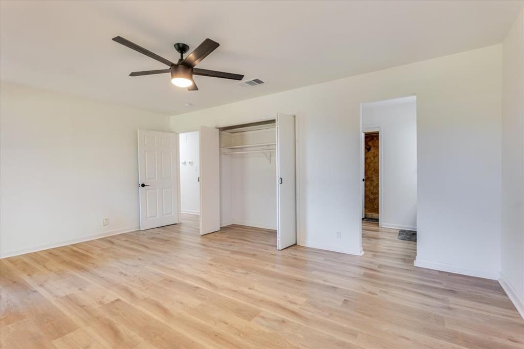8105 Ravenswood Road Granbury, TX 76049 - Photo 12 of 28 Expansive room featuring wood-finish flooring, a contemporary ceiling fan, and a built-in closet with bifold doors