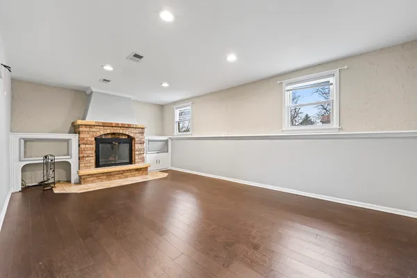an empty room with wooden floor a fireplace and window