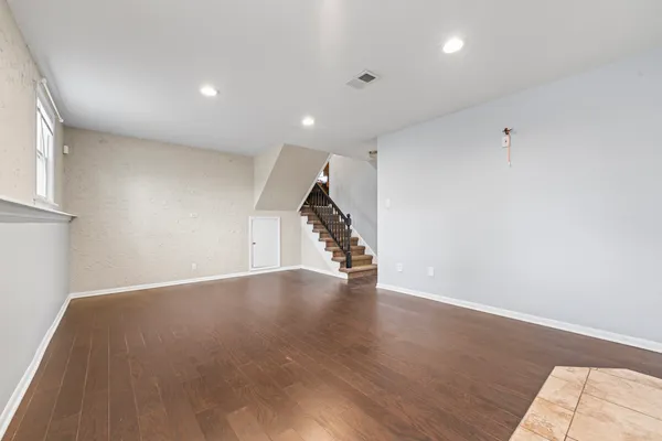 a view of an empty room with wooden floor and stairs