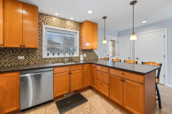 a kitchen with stainless steel appliances granite countertop a sink a stove and a wooden cabinets