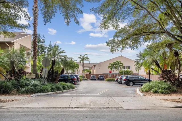 a view of road with card parked on side and retail shops