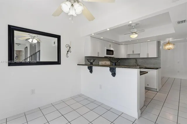 a kitchen with granite countertop white cabinets and black appliances