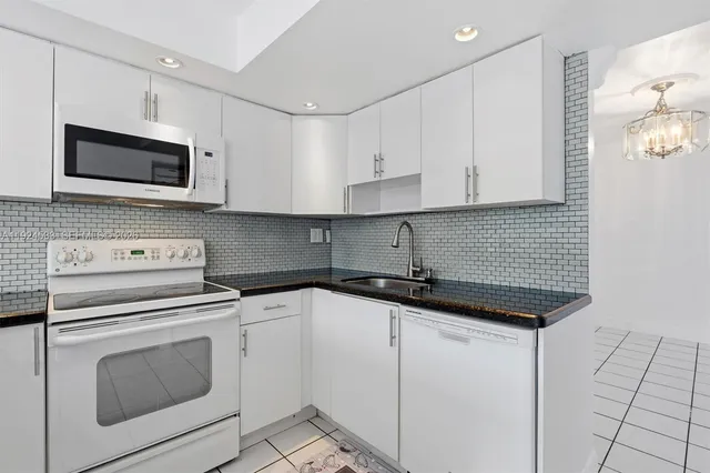 a kitchen with white cabinets and appliances