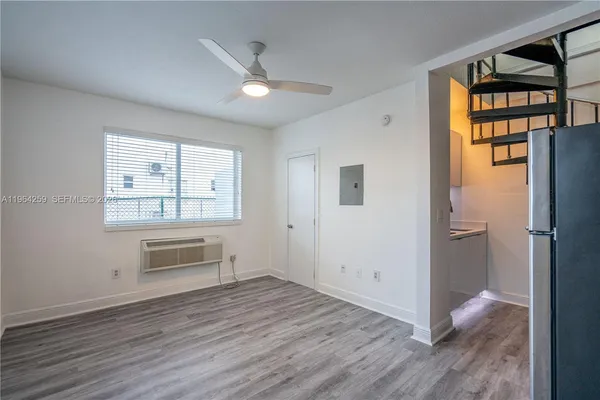 an empty room with wooden floor cabinet and windows