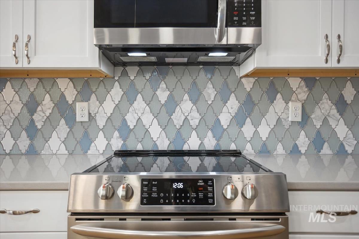 3729 South Maple Ridge Avenue Nampa, ID 83686 - Photo 16 of 46 Kitchen featuring stainless steel appliances, decorative backsplash, white cabinets, and light stone countertops