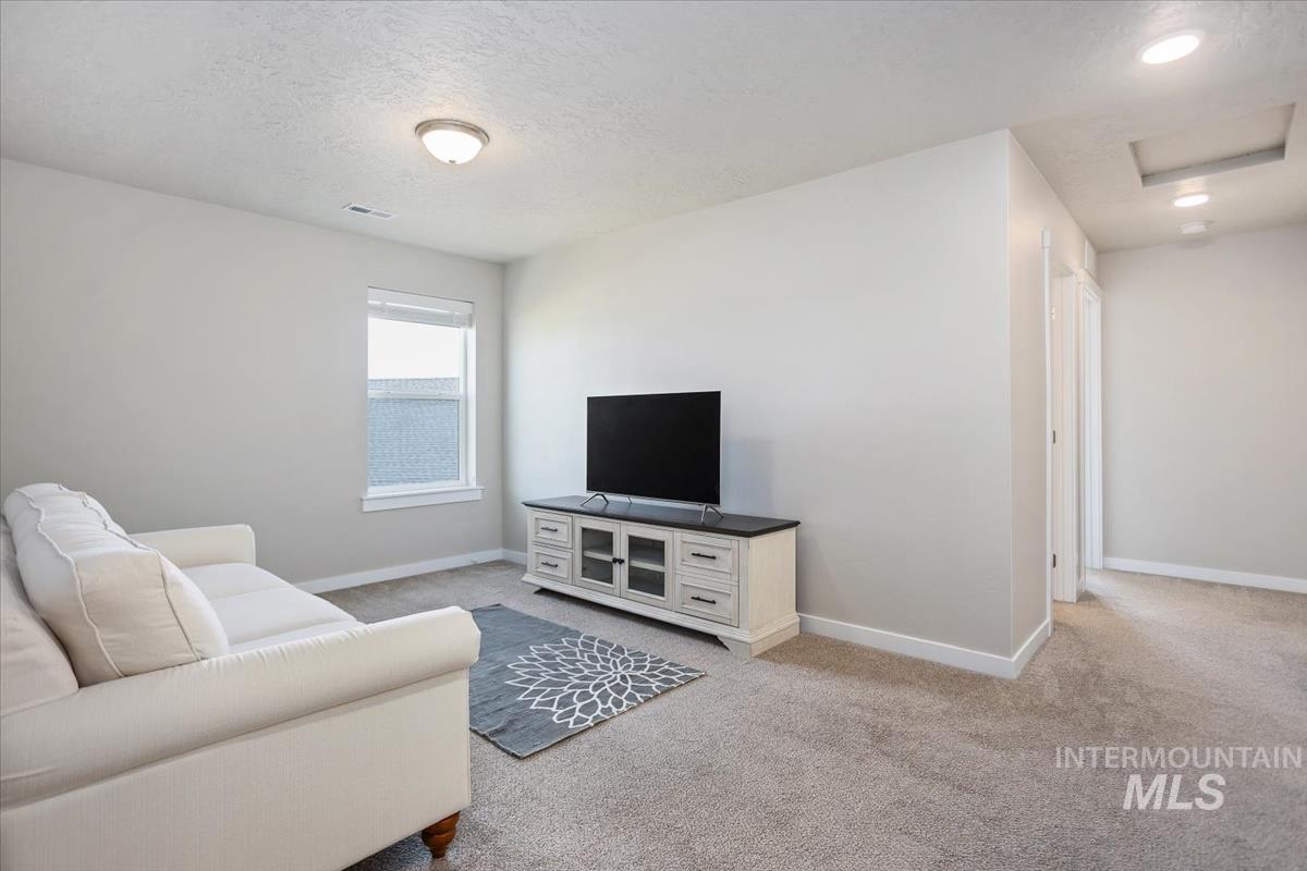 3729 South Maple Ridge Avenue Nampa, ID 83686 - Photo 20 of 46 Living room featuring light carpet and a textured ceiling
