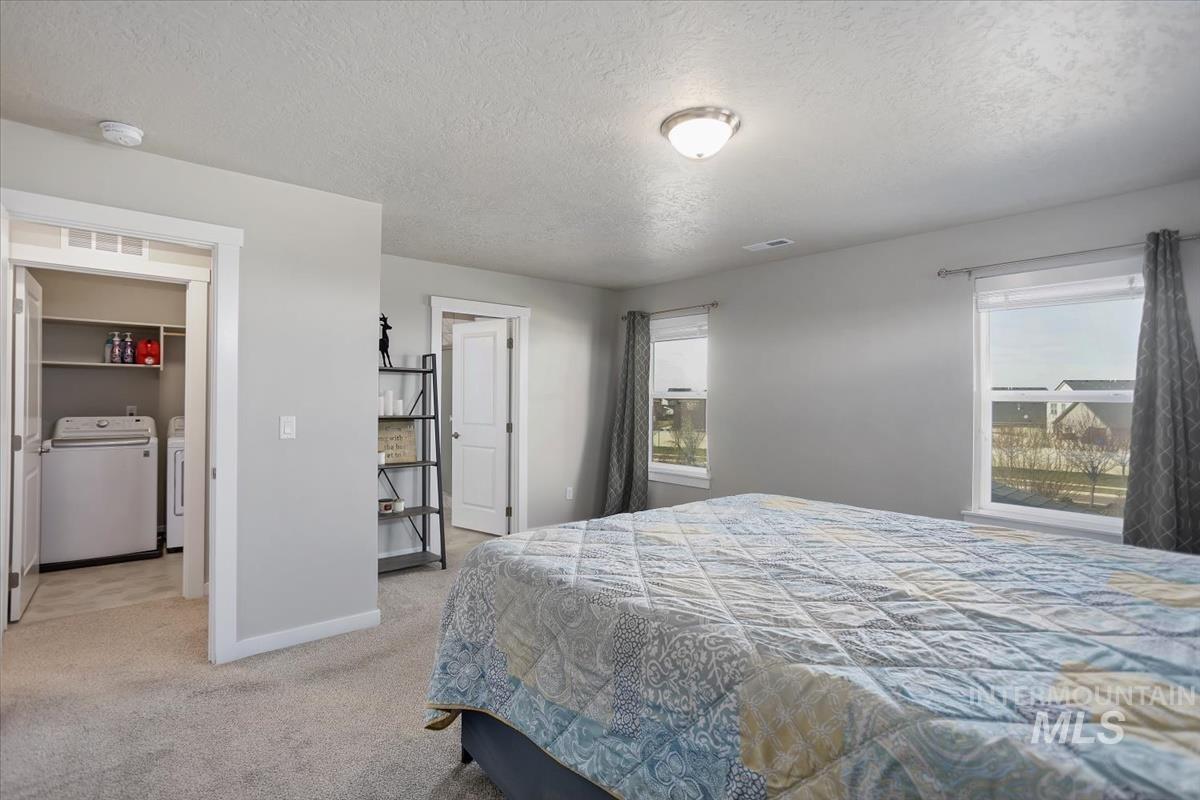 3729 South Maple Ridge Avenue Nampa, ID 83686 - Photo 22 of 46 Bedroom with a textured ceiling, separate washer and dryer, multiple windows, and light carpet