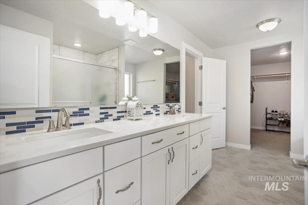 3729 South Maple Ridge Avenue Nampa, ID 83686 - Photo 24 of 46 Bathroom with a walk in closet, double vanity, a shower stall, and tasteful backsplash