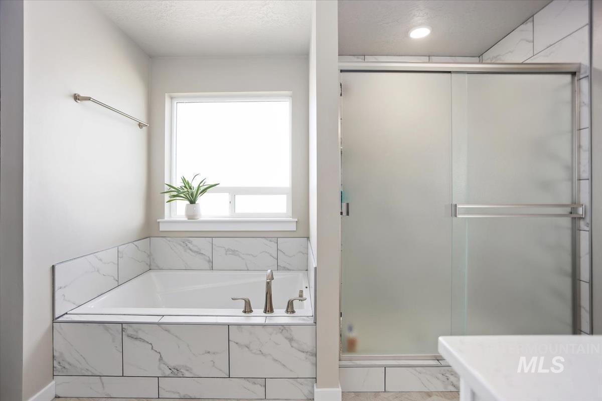 3729 South Maple Ridge Avenue Nampa, ID 83686 - Photo 25 of 46 Bathroom with a shower stall, a bath, and a textured ceiling