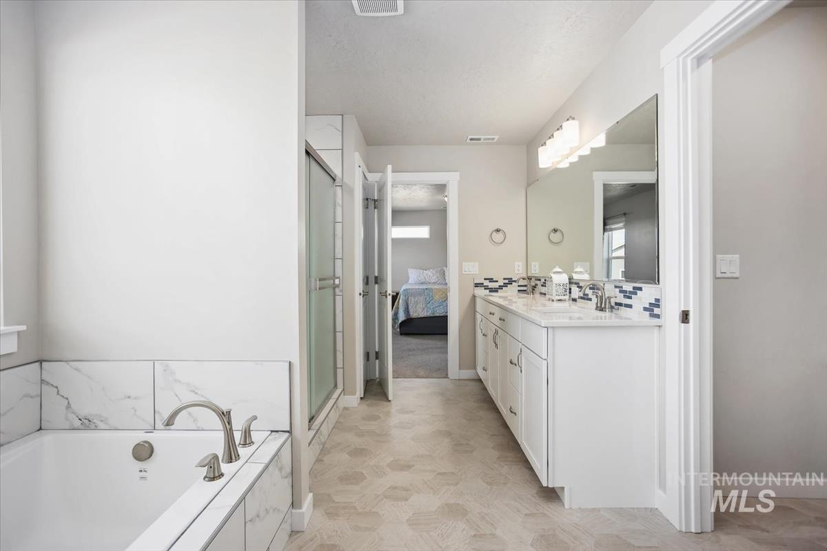 3729 South Maple Ridge Avenue Nampa, ID 83686 - Photo 26 of 46 Ensuite bathroom featuring vanity, a bath, and a stall shower