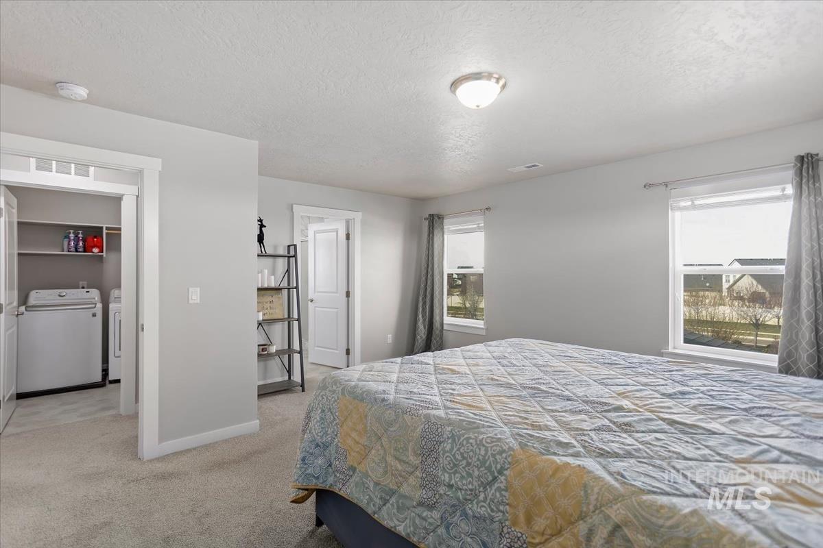 3729 South Maple Ridge Avenue Nampa, ID 83686 - Photo 28 of 46 Bedroom with a textured ceiling, light carpet, and washing machine and clothes dryer