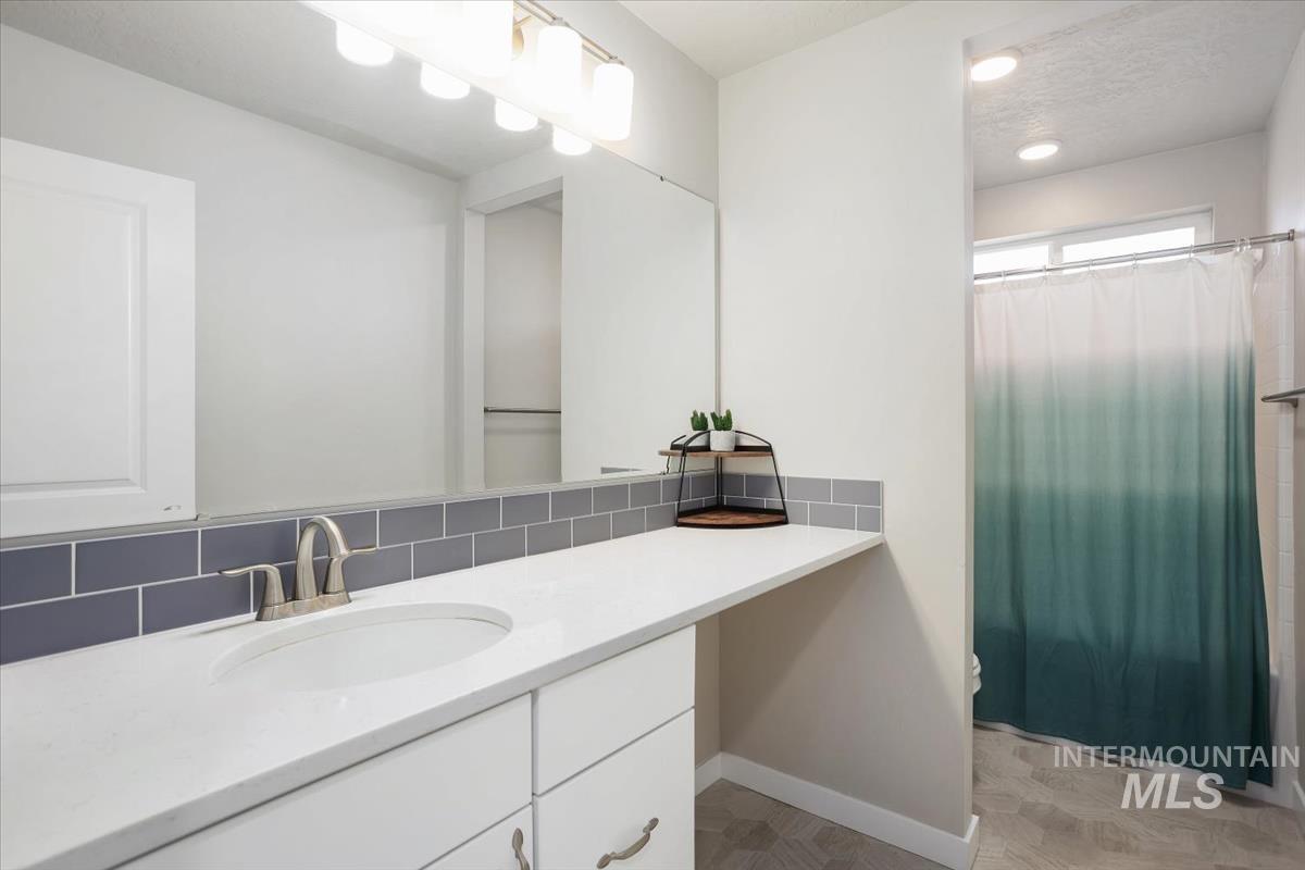 3729 South Maple Ridge Avenue Nampa, ID 83686 - Photo 34 of 46 Bathroom featuring vanity, shower / bath combination with curtain, and decorative backsplash