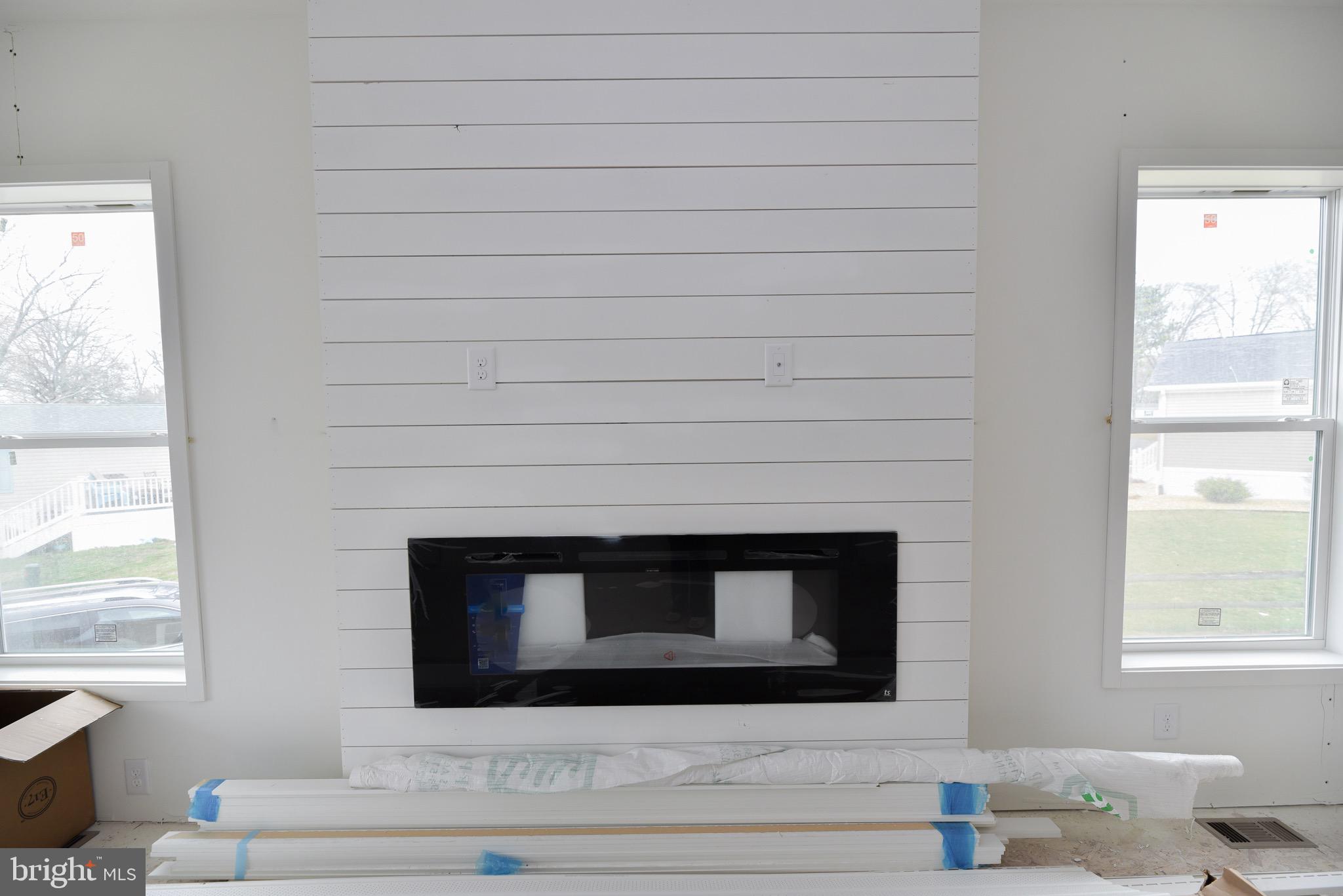 34340 River Road, Unit 129 Long Neck, DE 19966 - Photo 8 of 16 a living room with a fireplace and windows