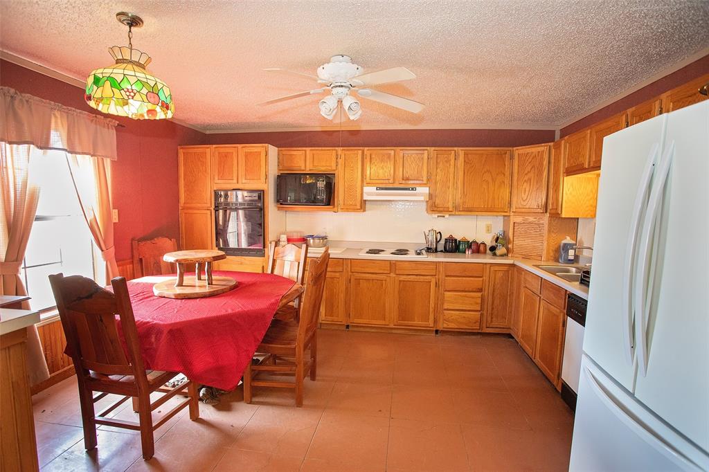 1193 Eastside Lake Road Graham, TX 76450 - Photo 22 of 38 a kitchen with a refrigerator a stove a sink dishwasher with a dining table and chairs