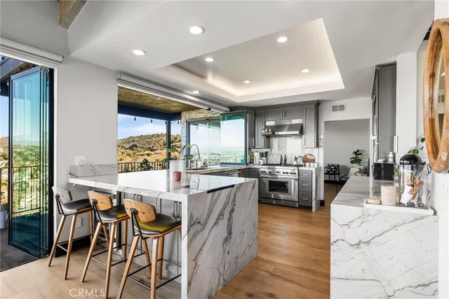 a view of a kitchen with kitchen island wooden floors and stainless steel appliances