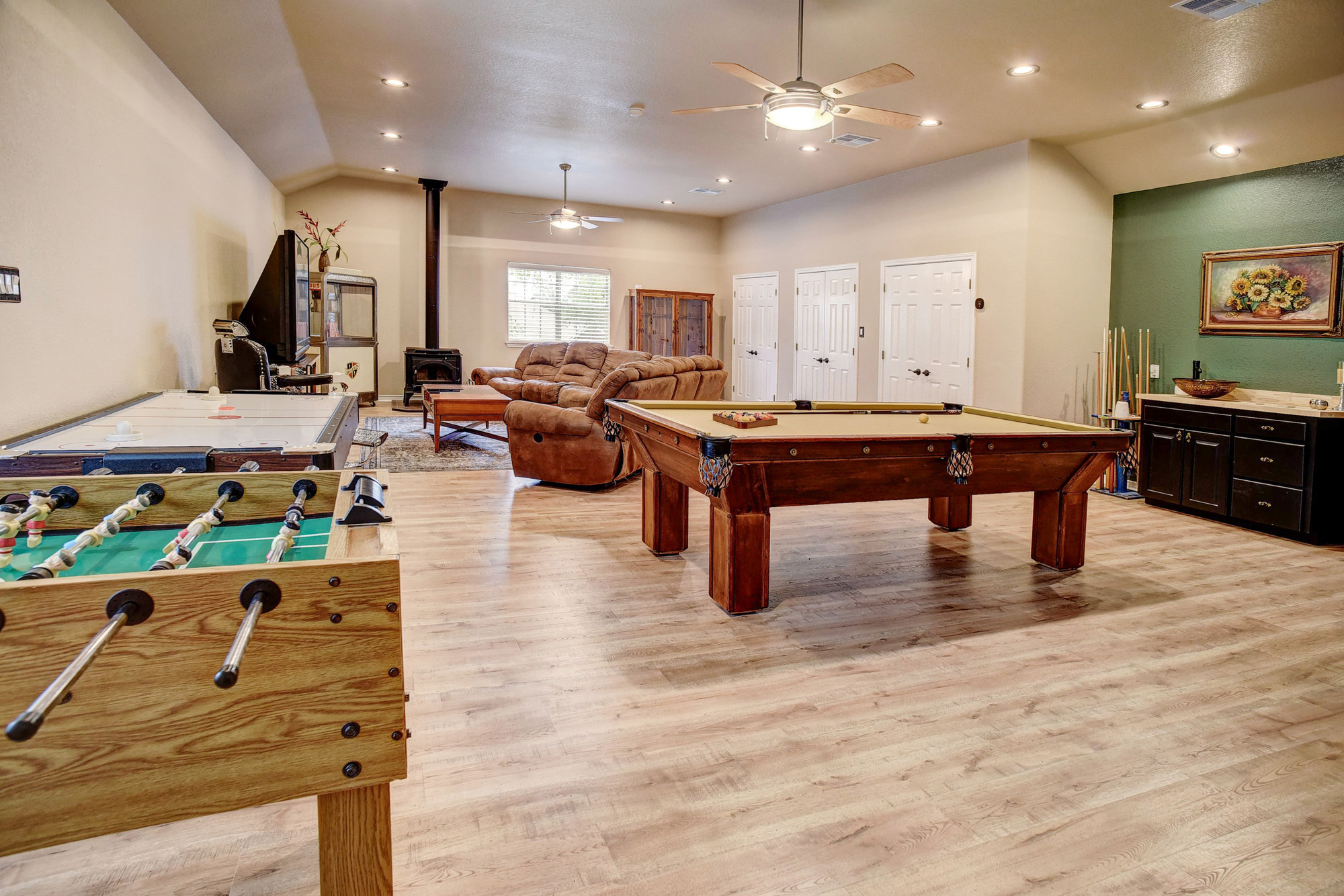 147 Spring Meadow Road Bastrop, TX 78602 - Photo 21 of 40 Spacious recreational room featuring vaulted ceilings, wood-finish flooring, recessed lighting, and a prominent wood-burning stove