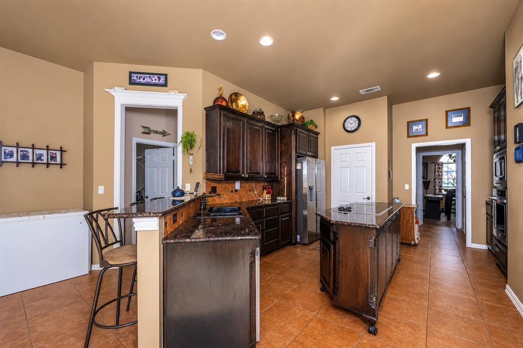 100 Manders Court Runaway Bay, TX 76426 - Photo 8 of 33 a kitchen with stainless steel appliances kitchen island granite countertop a refrigerator a stove a sink and a dining table with wooden floor