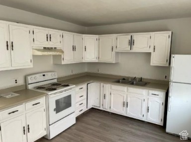 590 Pilot Avenue Wendover, UT 84083 - Photo 9 of 20 Kitchen with white appliances, white cabinets, dark wood-type flooring, extractor fan, and light countertops
