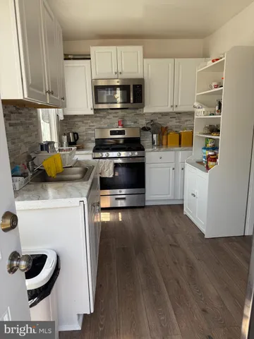 a kitchen with granite countertop a sink a stove and cabinets