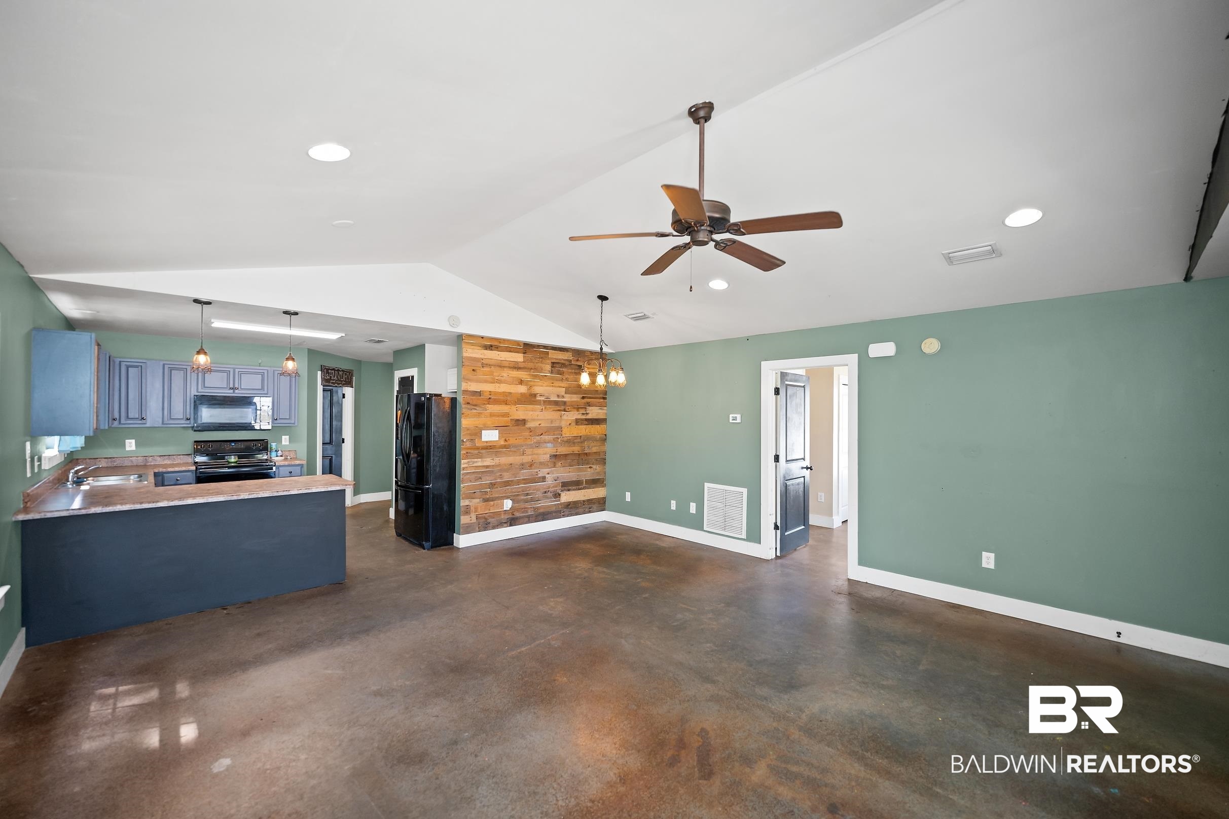 2000 Maria Lane Lillian, AL 36549 - Photo 4 of 35 Unfurnished living room with finished concrete floors, a ceiling fan, wooden walls, and vaulted ceiling