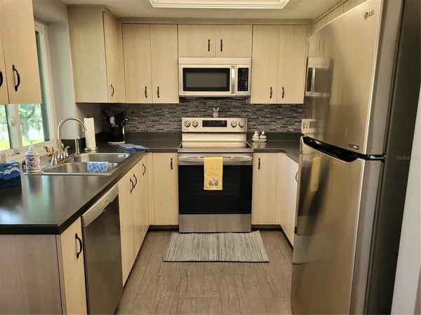 a kitchen with stainless steel appliances granite countertop a refrigerator a stove a sink and a microwave