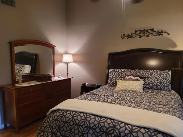 a bedroom with a bed and a lamp on dresser