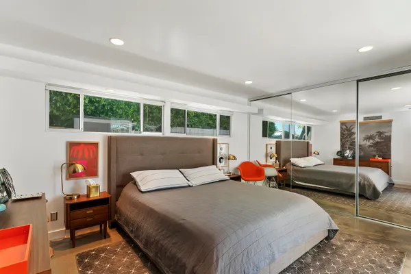 a bedroom with a bed a large window and potted plant on the dresser