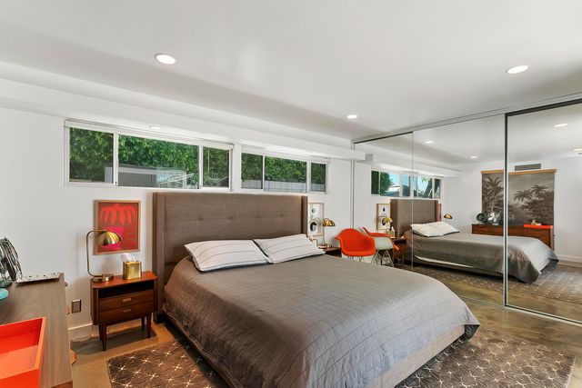 a bedroom with a bed a large window and potted plant on the dresser