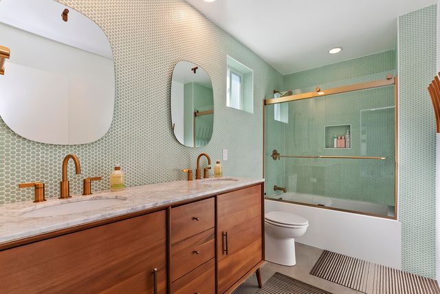 a spacious bathroom with a double vanity sink toilet mirror and shower