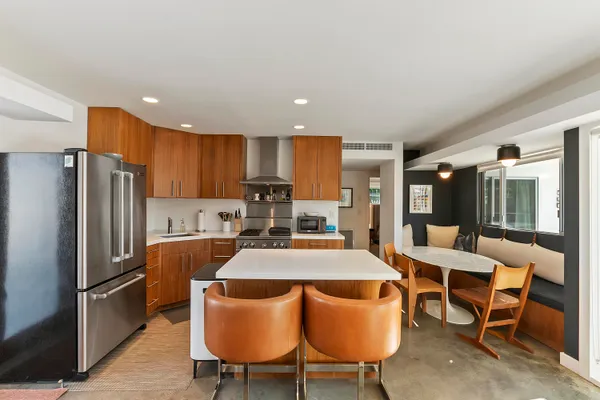 a kitchen with stainless steel appliances granite countertop a dining table chairs refrigerator and microwave