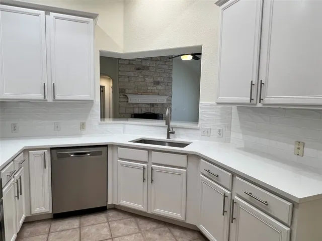 a kitchen with white cabinets sink and dishwasher