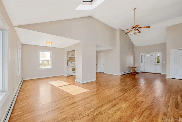 a view of empty room with wooden floor and ceiling fan