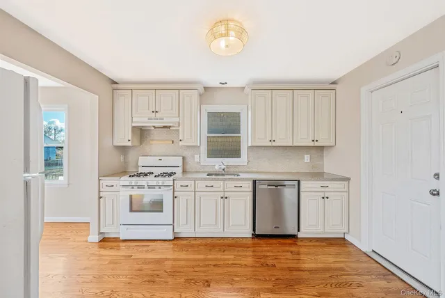 a kitchen with stainless steel appliances granite countertop a stove a sink and white cabinets