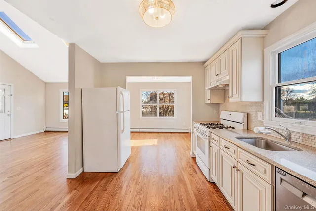 a kitchen with wooden floors and a view of living room