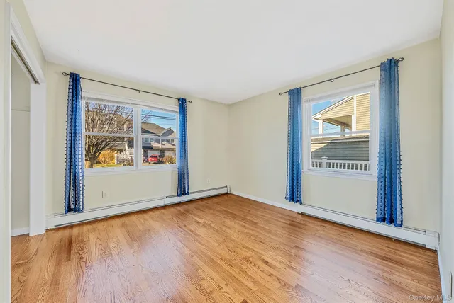 a view of an empty room with window and wooden floor