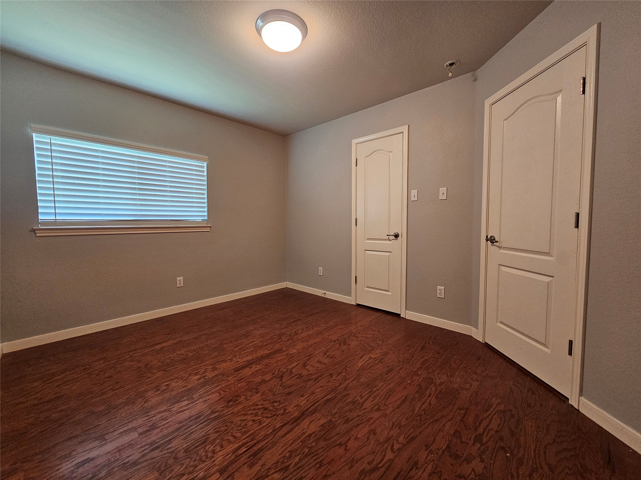 2035 Intrepid Drive Buda, TX 78610 - Photo 20 of 26 Rich hardwood flooring complements the neutral tones of this inviting bedroom space.