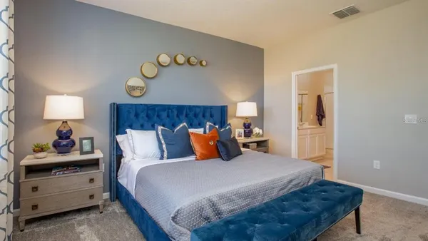 a bedroom with a bed and a lamp on dresser
