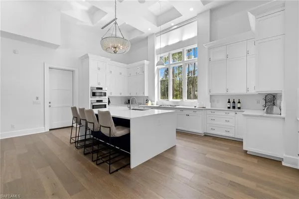 a large white kitchen with a large window and stainless steel appliances