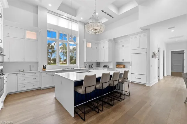 a large white kitchen with a stove a sink dishwasher and a refrigerator with wooden floor