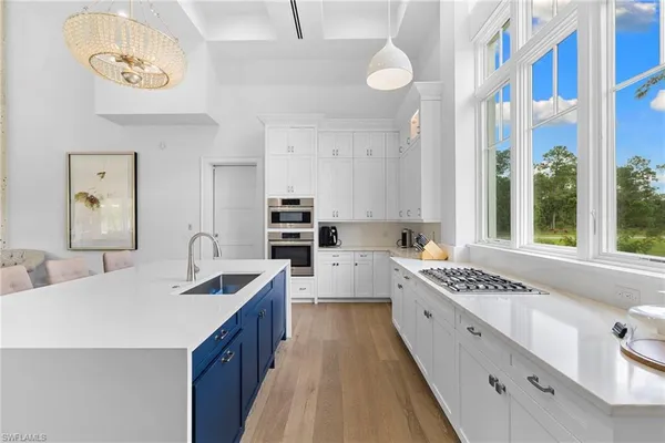 a kitchen with stainless steel appliances granite countertop a sink a stove and white cabinets