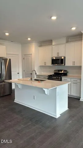 a kitchen with stainless steel appliances a stove a sink a refrigerator a microwave and cabinets