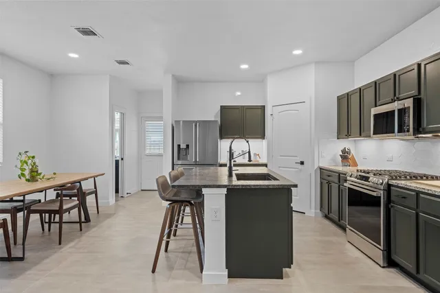 a kitchen with stainless steel appliances kitchen island granite countertop a stove a sink and a microwave